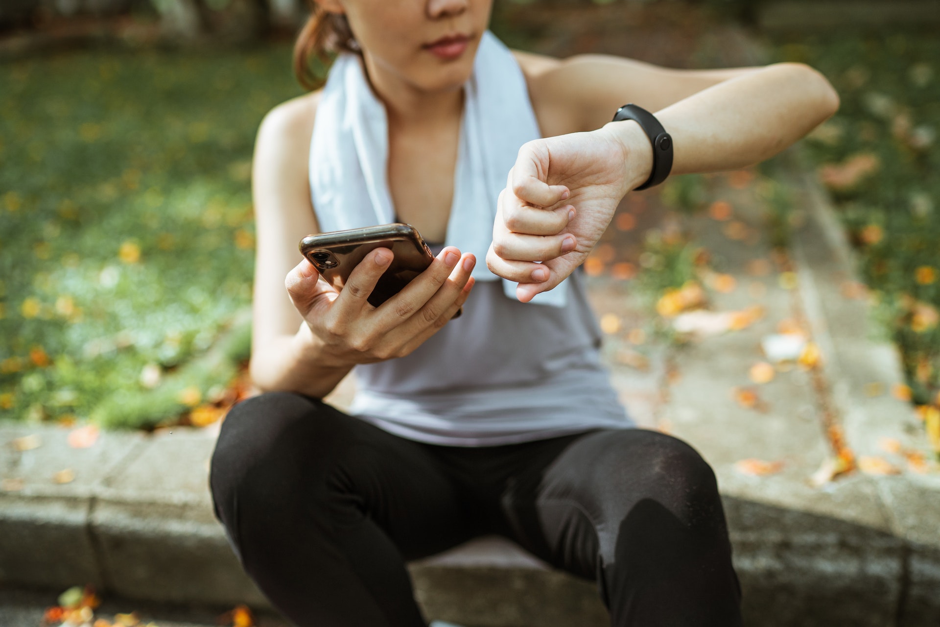 Una donna fa il pairing tra smartphone e smartband durante una sessione di jogging